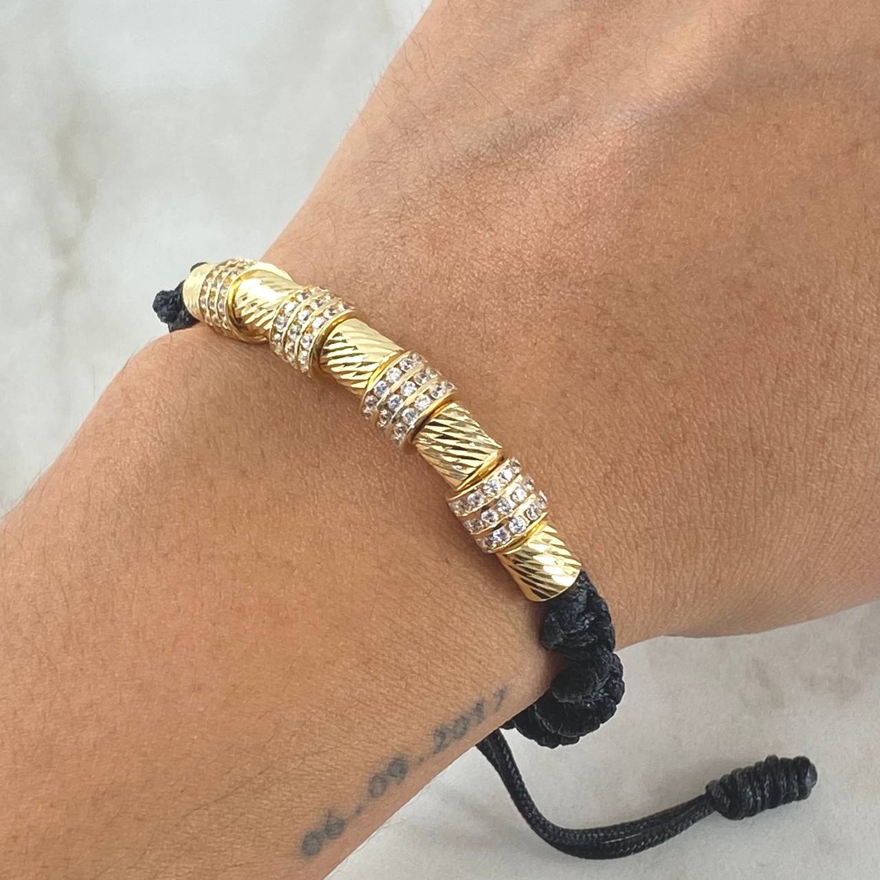 Pulsera Negra Herraje Rueda Triple Circones Blancos 6.1gr / 6mm Cilindros Diamantados 5und Oro Amarillo 18K ©